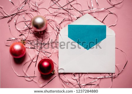 Christmas composition. Envelope with a card. Christmas red and pink decorations on pink background.
