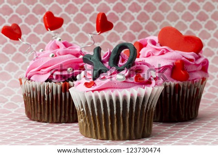 Close-up image of strawberry cupcakes with heart shape and alphabets.