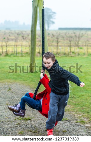 A handsome little boy with ADHD, Autism, Aspergers Syndrome plays with his little sister at the park, having fun and bonding together