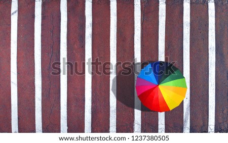 Lonely pedestrian with a colorful umbrella on a pedestrian crossing. Aerial. Top view. Peace and harmony concept background.