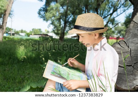 A little boy painting at tree