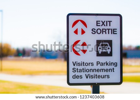 Exit and Visitors Parking Sign post in bi-lingual Canada.  French Translation is Exit and Visitors parking