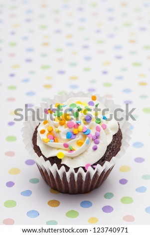 Image of a cupcake decorated with cream and sprinkles.