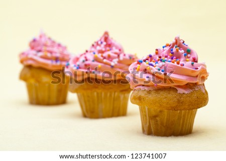 Cupcakes with strawberry icing displayed on plain background.