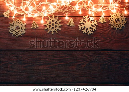 Photo of New Year's wooden red table with burning garland on top, snowflakes.