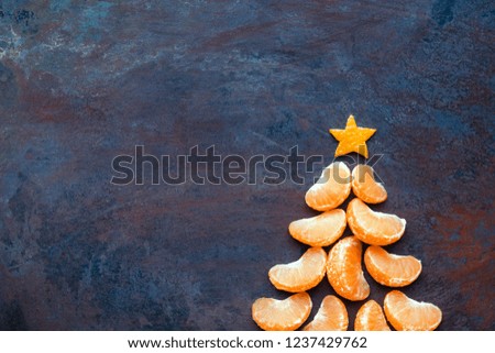Tangerine christmas tree  on dark rust metal grunge background. Xmas festive greeting card with a tree of orange tangerine slices and star, copy space, flat lay