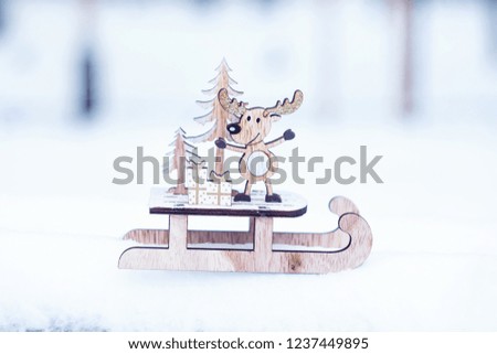 Christmas winter holiday festive background.  Wooden cute reindeer on sled, red gift boxes on white snow and green christmas trees outdoor. Christmas composition decoration, Xmas  gift concept
