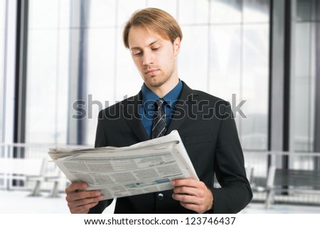 Portrait of a young businessman reading a newspaper