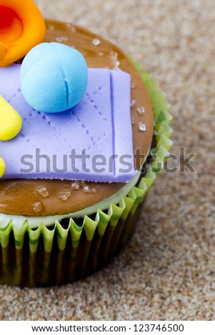 Close cropped image of a cupcake with miniature looking items on top on a textured surface.