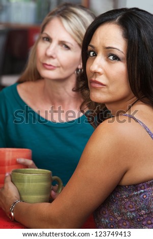Concerned Hispanic and Caucasian ladies sitting in restaurant Royalty-Free Stock Photo #123749413