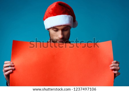 man in santa hat looks at red mockup                