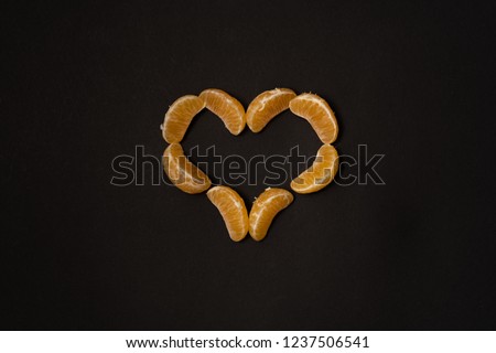 Heart made of tangerine slices on a black background