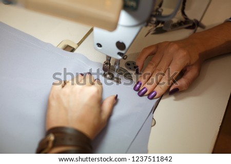 View from above on hands of female tailor working on sewing machine.  dress manufacturing industry.