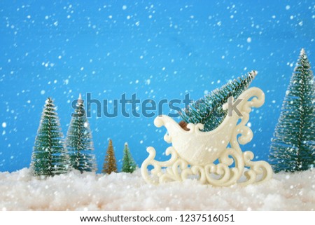 Image of christmas tree on the white glitter sled over snowy wooden table