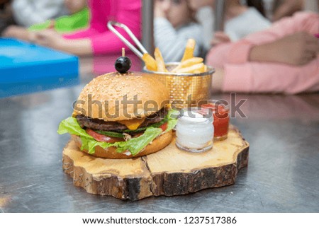 Big double hamburger with fried potato vegetables and beef on a wooden 