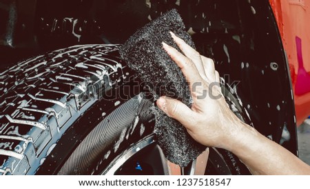 Car Care or Car Detailing Process. Using black sponge to washing the tire.