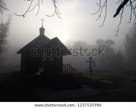 A small village church in the fog. Gloomy landscape.