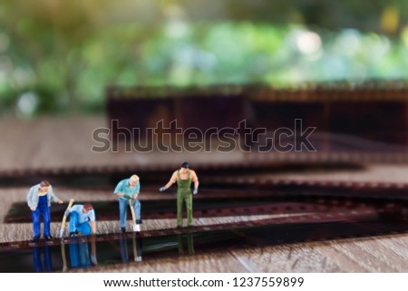 Miniature mini  figures technician verify old film strip and remove image from film. Changing from film to digital image cocept.