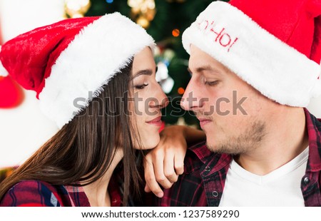 
Merry Christmas and New Year. A young couple celebrates Christmas and New Year at home near the Christmas tree with gifts