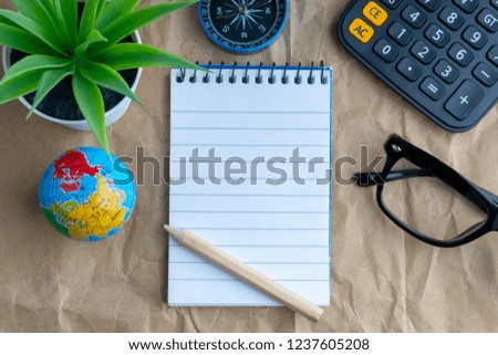 Notepad, flower vase, spectacle, pencil, compass, calculator and mini globe on wooden paper background. Business and education concept. Copy space