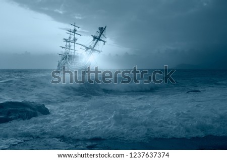 Sailing old ship in storm sea against amazing sunset Royalty-Free Stock Photo #1237637374