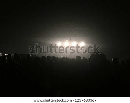 Bright white light from the music stage, silhouette of people