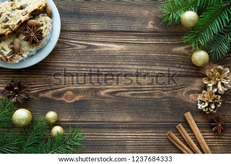 Christmas holiday mood background, traditional Christmas cake, golden Christmas balls and golden cones, fir tree branches decorations on brown wooden table. Copy space. 