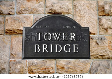 Tower Bridge sign in London in the background a sandstone wall