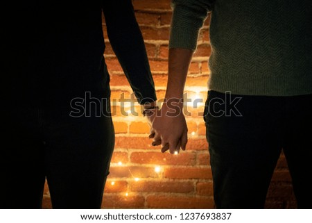 Couple hand taken shape with blurred night light,defocus, bokeh,night concept,beautiful Valentine lights or christmas celebrating in front of brick wall. Romantic background.