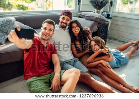 Cropped shot of four happy friends taking a selfie in the living room