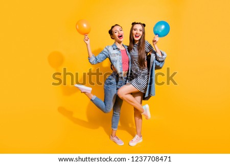 Full legs length body size portrait of two funky funny brunette hair lady stand isolated on yellow vivid background with fly ball in hands make beaming wide toothy smile