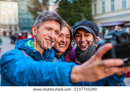 Friends take a selfie. Three friends are walking through the beautiful old town. Travel to European cities. Two women and a man are photographed against the backdrop of old buildings.