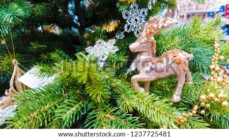 Beautiful Christmas ornaments. Christmas decoration in the form of the golden reindeer with glitters, in the background, branches Christmas tree.