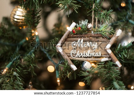 Seasonal Idea of Festive Holiday Photo with Cute Wooden Arrow Ornament with Merry Christmas in Script Font inside Christmas Tree with Bright White Lights and Gold Ornaments as Decorations