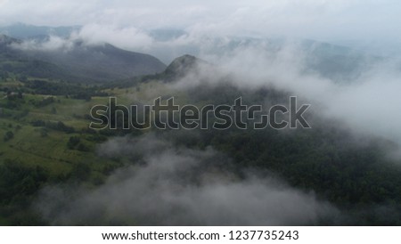 aerial fly over clouds on rainy cloudy day in forest mountains
