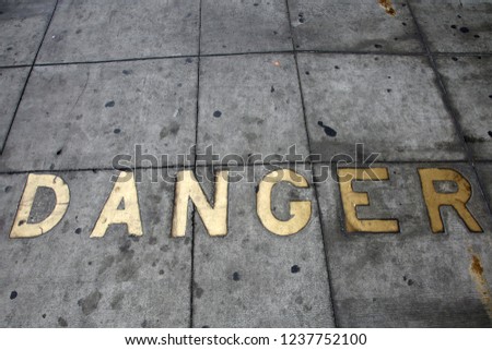 Metal Words in the Sidewalk. Old Metal Words imbedded in cement. The word DANGER written in Brass Letters Cemented into the sidewalk.