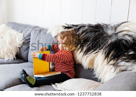 Toddler girl on sofa reading picture book - Hindeloopen, Friesland, Netherlands