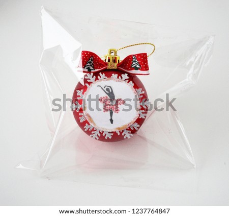 Red Christmas ball in packing, decorated with sequins, ribbons, with ballerinas