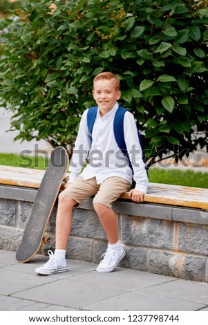 Happy smiling school boy with backpack and skateboard outdoors. Childhood, leisure, school and people concept.
