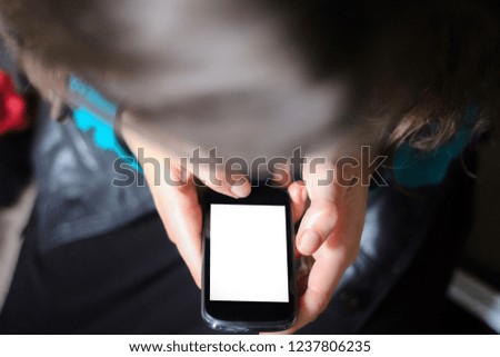 Top view of young girl holding and looking at smart phone 