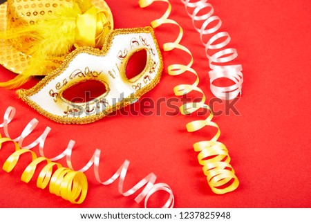 Yellow and white carnival mask on red background. Top view image of masquerade background. Flat lay. Mardi Gras celebration concept. Copy space.