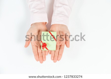 Hands holding craft paper gift box with as a present for Christmas, new year, valentine day or anniversary on white background, top view