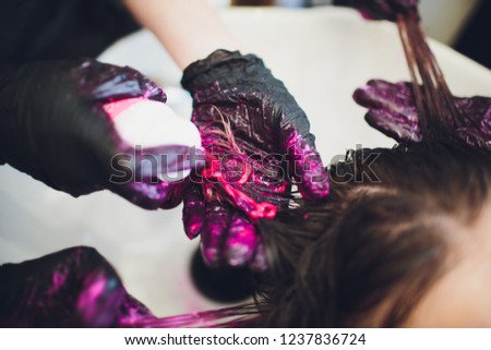 Beautician dying hair of woman. Girl in beauty salon.