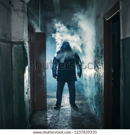 Silhouette of man in dark creepy corridor in clouds of vape steam or vapor smoke, mystery horror atmosphere, toned