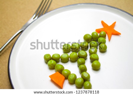 Funny edible Christmas tree made from peas and carrots, Breakfast idea for kids. New Year food background top view . holiday, celebration, food art concept