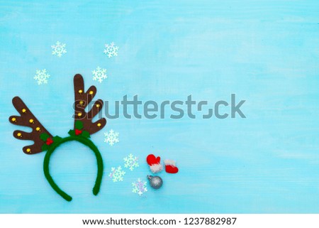 Christmas background with carnival festival deer horns with bells, silver ball, snowflakes. Christmas decorations on a blue wooden table