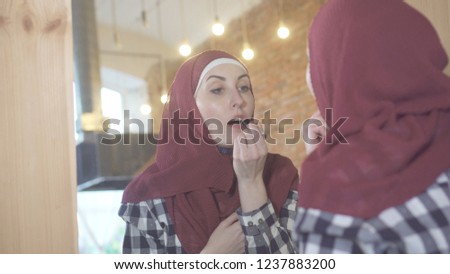 Young pretty muslim woman in a hijab in front of a mirror 
