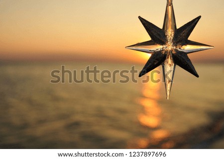 Christmas decoration star on the background of the sunset on the sea.
