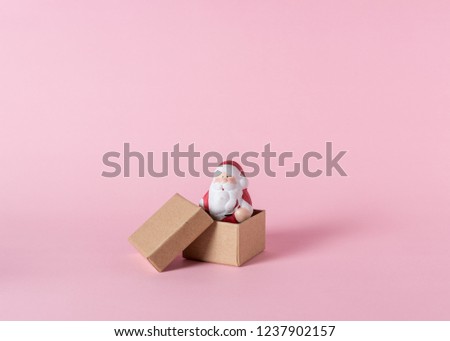 Small Santa Claus with gift boxes on pink background. Minimal Christmas or New Year concept.