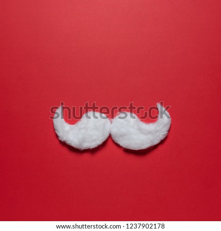 White hipster mustache of Santa Claus on red background. New Year or Christmas minimal concept.